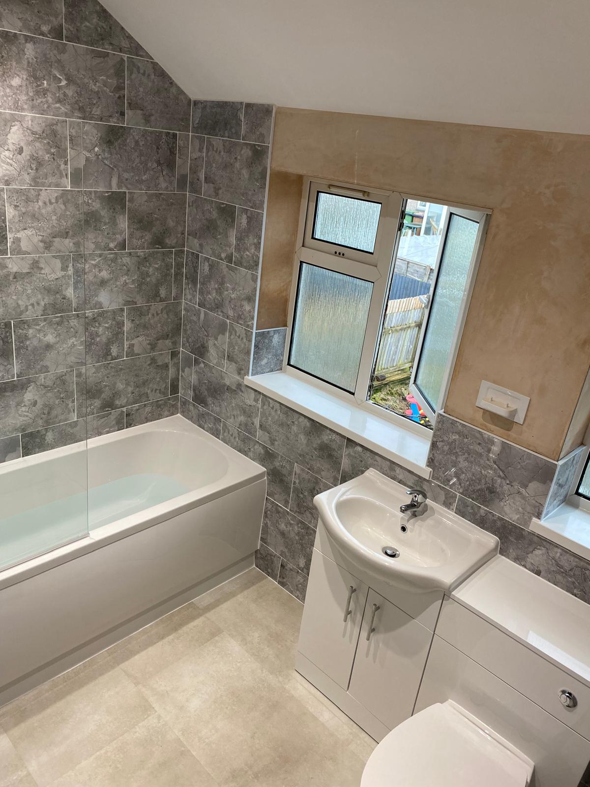 Finished bathroom with bath and tiled walls